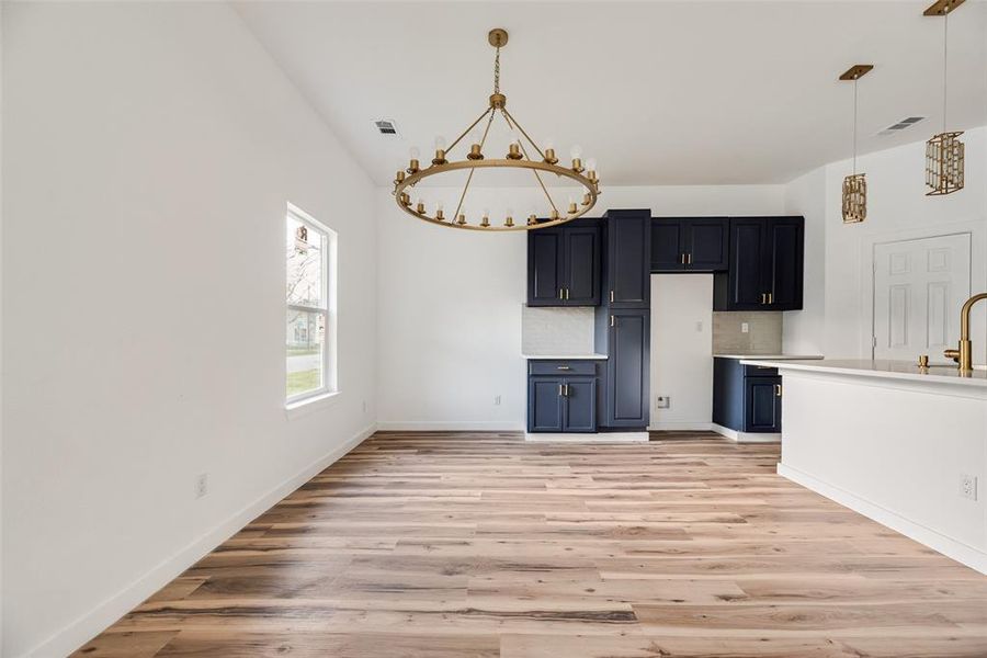 Kitchen featuring light countertops, hanging lights, light wood-style flooring, and tasteful backsplash
