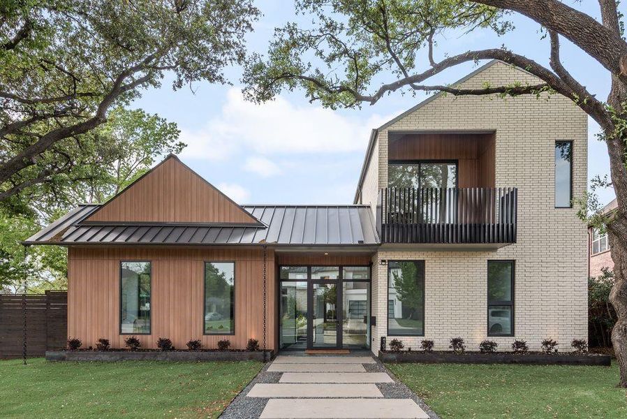 Front elevation showcasing a striking blend of materials, where warm natural textures meet modern architectural lines—framed by mature trees and anchored by a private balcony that enhances both form and function.