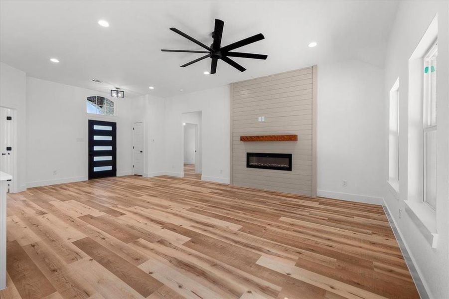 Unfurnished living room with a fireplace, ceiling fan, light hardwood / wood-style flooring, and a healthy amount of sunlight