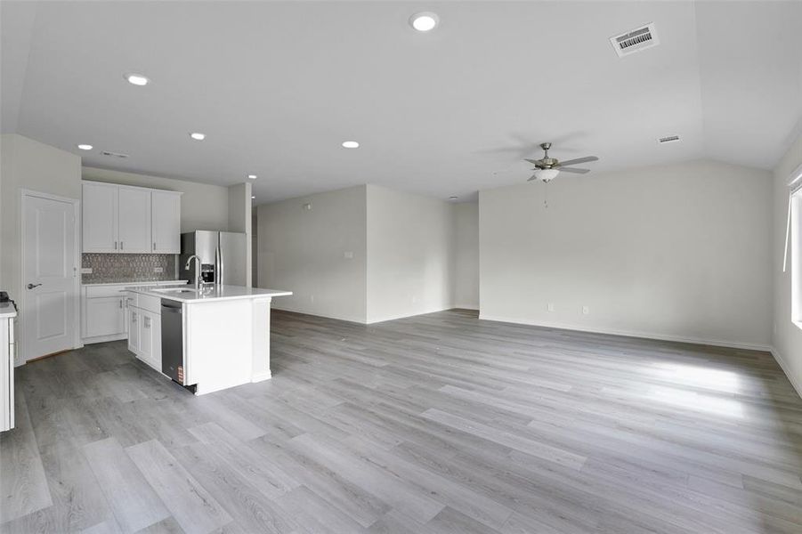 Kitchen with a center island with sink, white cabinets, light wood-style flooring, open floor plan, and tasteful backsplash Kitchen with a center island with sink, white cabinets, light wood-style flooring, open floor plan, and tasteful backsplash