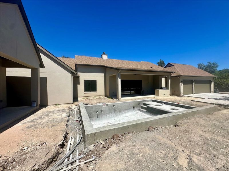 An in-progress concrete pool anchors the backyard of this modern estate with detached garages.