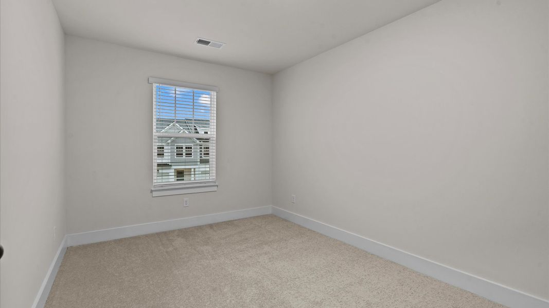 Accomplished bedroom layout with cozy carpet, a spacious walk-in closet, and sun-filled windows