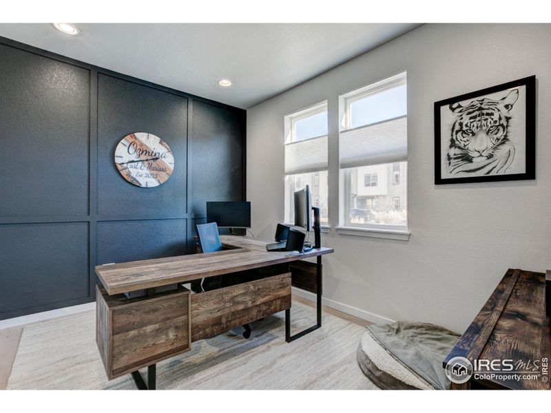 Main level Office/Flex room with custom wall treatment and engineered hardwood flooring. Custom window blinds throughout the home