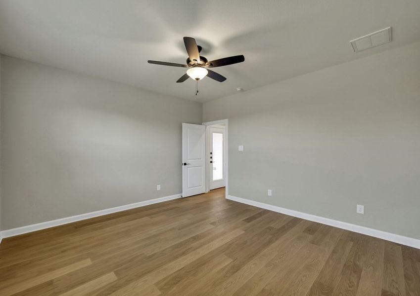 Primary bedroom featuring a ceiling fan and wood-look flooring with a doorway to the ensuite bath.