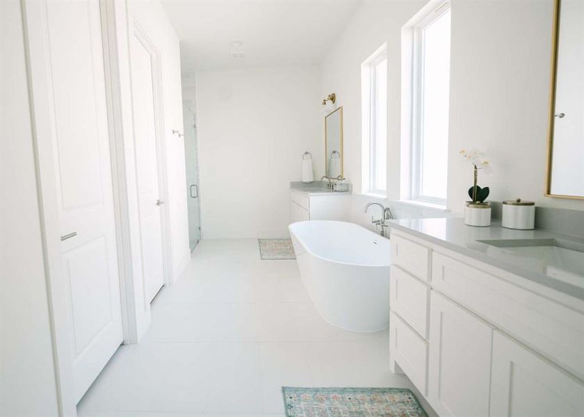 Bathroom with tile floors, a bath to relax in, and vanity