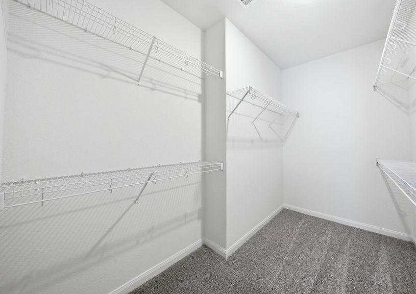 Primary walk-in closet featuring built-in wire shelving. Primary walk-in closet featuring built-in wire shelving.