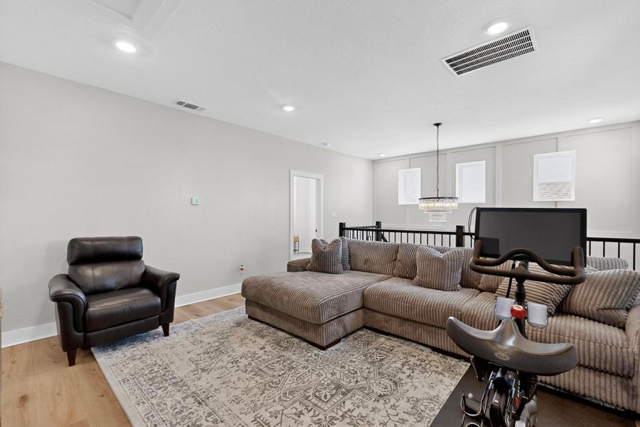 Living area with light wood-style floors, recessed lighting, and a chandelier