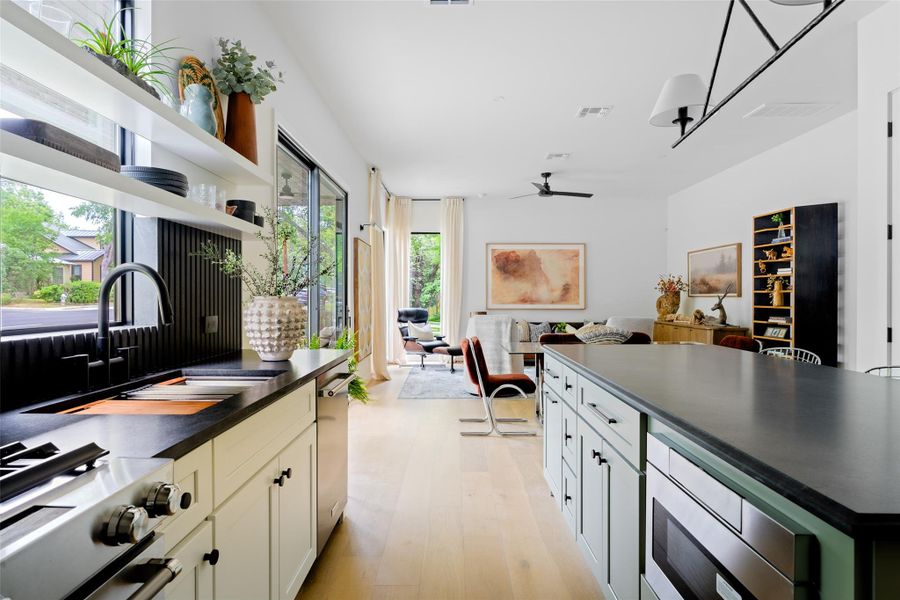 Kitchen featuring dark countertops, open floor plan, ceiling fan, a sink, and stainless steel appliances