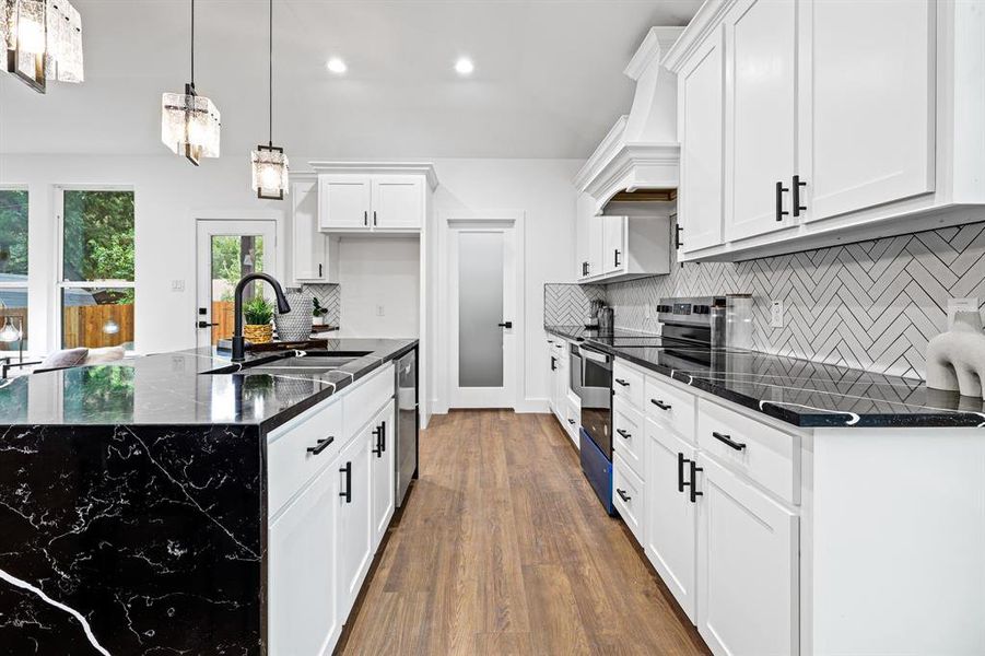 Kitchen featuring dark hardwood / wood-style floors, stainless steel appliances, sink, premium range hood, and white cabinets