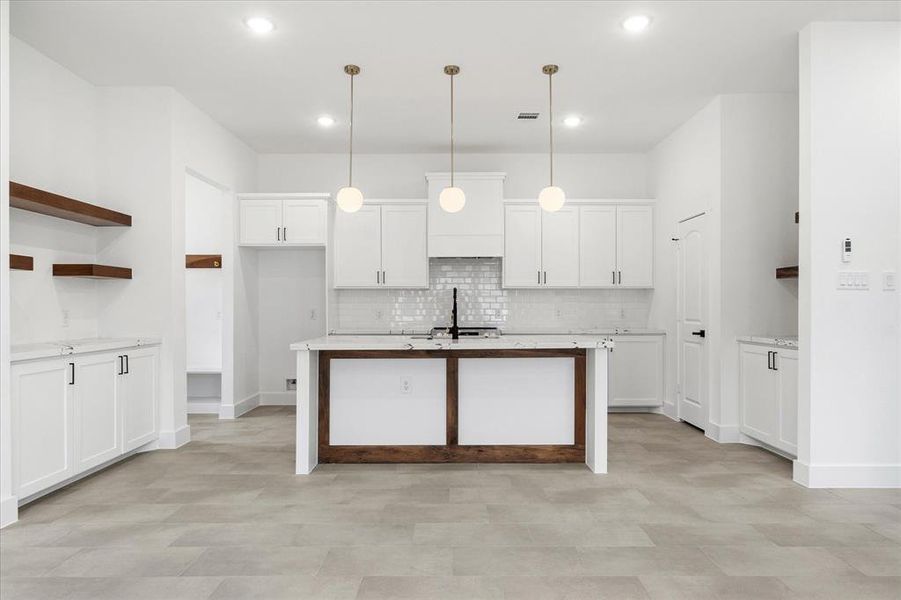 Three pendant lights illuminate your large island with additional seating, and the wood accents add a touch of warmth to this elegant space.