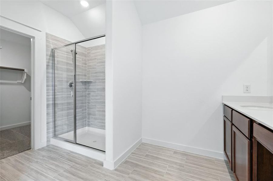 Full bathroom with vanity, a stall shower, a walk in closet, and lofted ceiling Full bathroom with vanity, a stall shower, a walk in closet, and lofted ceiling
