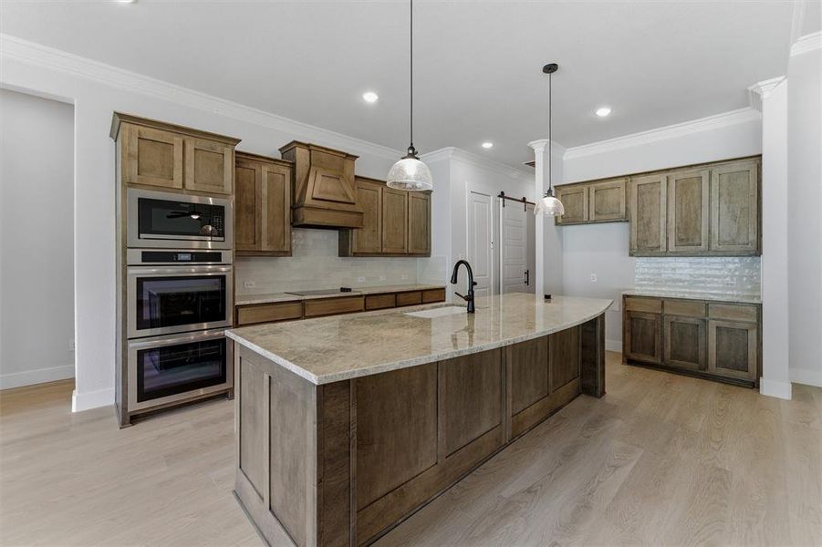 Gourmet kitchen featuring a large curved island with a single basin sink and gooseneck faucet