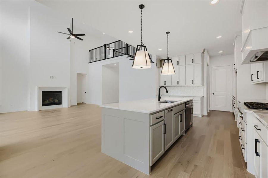 Spacious kitchen featuring a large island with quartz countertop, white cabinetry with black hardware, and stainless steel appliances Spacious kitchen featuring a large island with quartz countertop, white cabinetry with black hardware, and stainless steel appliances