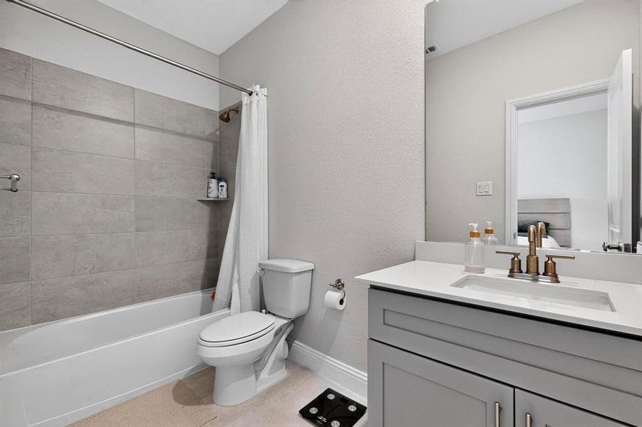 Full bath with shower / tub combo with curtain, vanity, and a textured wall Full bath with shower / tub combo with curtain, vanity, and a textured wall