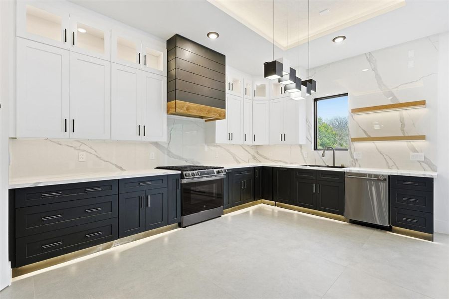 Two-tone cabinetry and under-cabinet lighting accent the kitchen, which also features a custom wood-trimmed vent hood.
