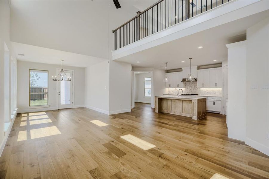 Open-concept living space featuring wood-finish flooring, a two-story ceiling, and a kitchen island with a sink