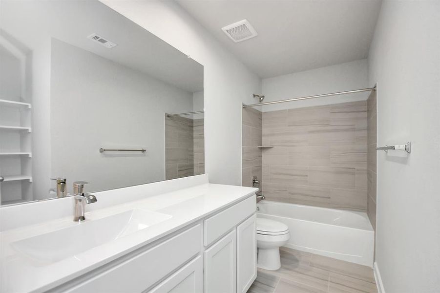 Experience sophistication in the secondary bathroom, where tile flooring complements a bath/shower combo with tile surround. Light colored cabinets complete with a beautiful light countertop, enhances the space for a truly inviting ambiance.