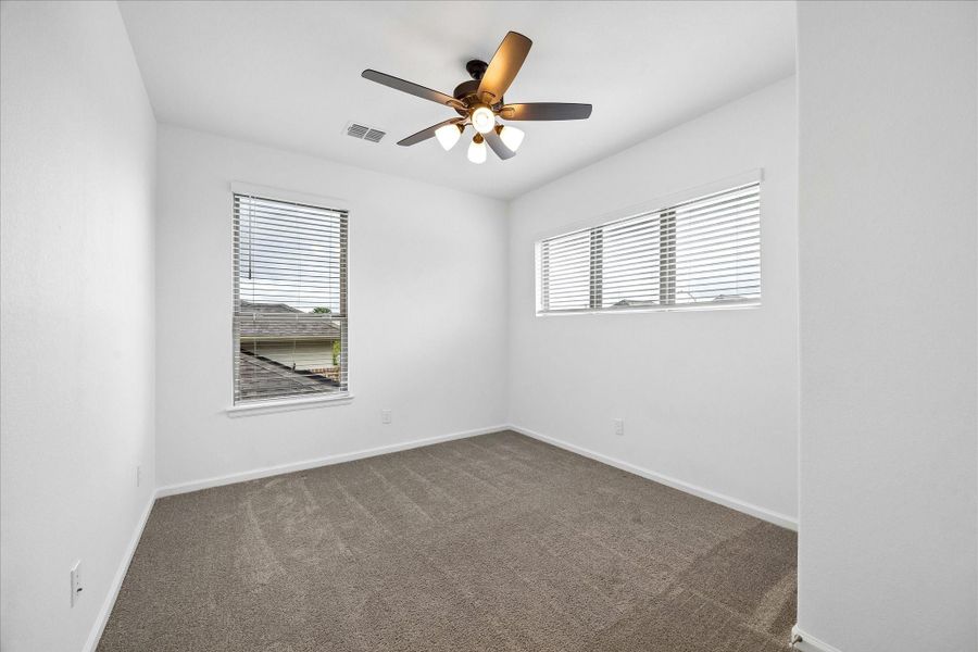 This upstairs guest bedroom offers a comfortable retreat with soft carpet, a cooling fan, a walk-in closet, and easy access to a nearby full bathroom. It’s a great setup for guests, hobbies, or anyone who wants their own private space.