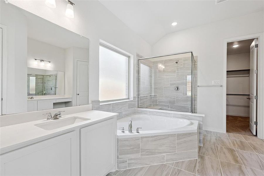 Bathroom featuring plus walk in shower, vanity, lofted ceiling, and tile patterned flooring