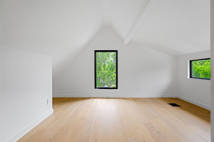 Bonus room featuring baseboards, vaulted ceiling, light wood finished floors, and visible vents