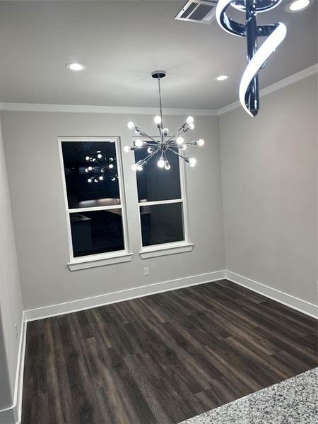 Unfurnished dining area with an inviting chandelier, dark hardwood / wood-style floors, and crown molding