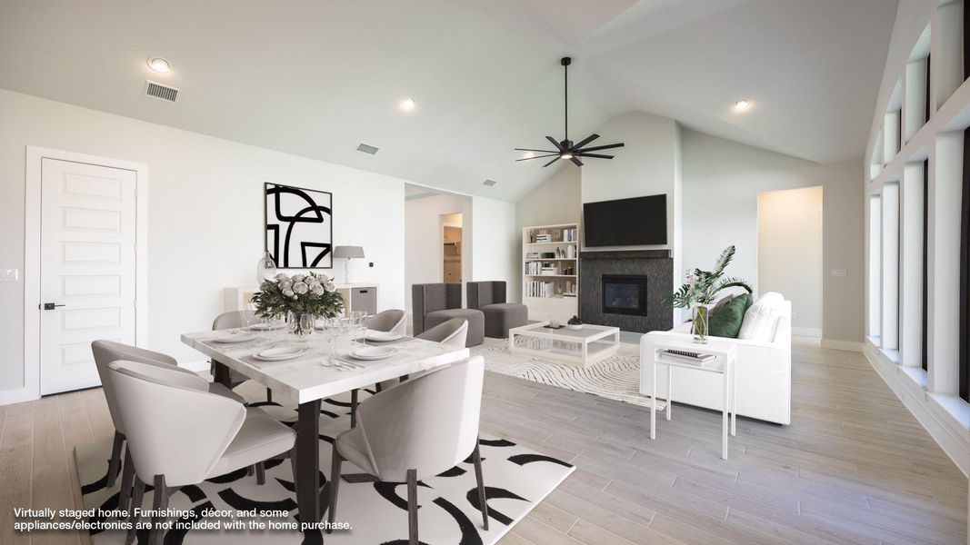 Dining area featuring a glass covered fireplace, light wood-style flooring, recessed lighting, high vaulted ceiling, and a ceiling fan Dining area featuring a glass covered fireplace, light wood-style flooring, recessed lighting, high vaulted ceiling, and a ceiling fan