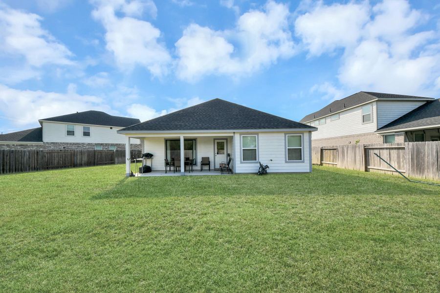 Full view of the rear facade highlighting the home's sturdy footprint, roofline, and deep yard perimeter.