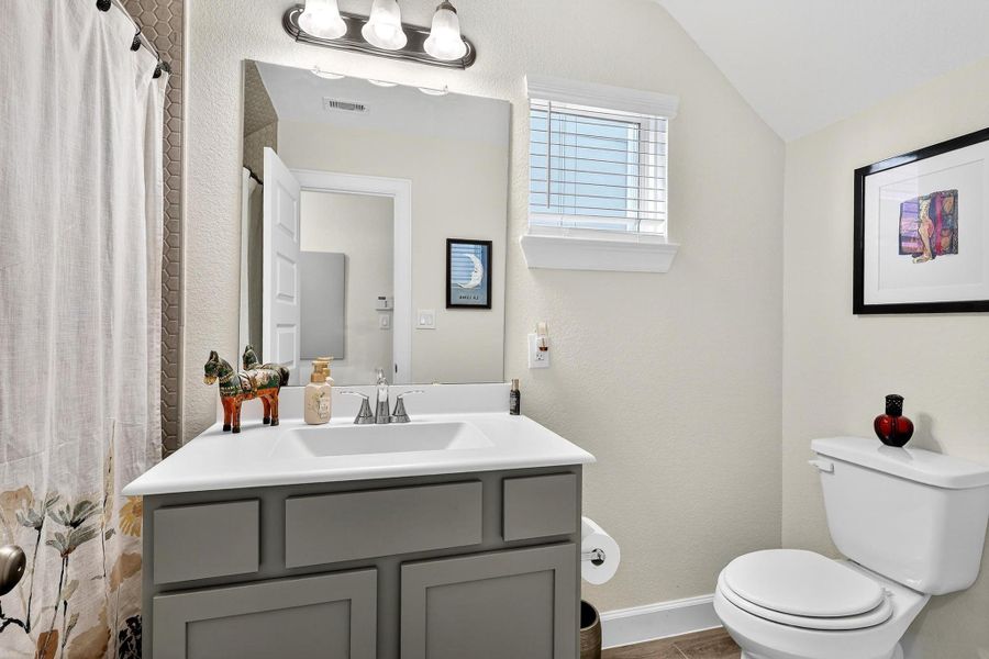 Modern hall bath with sleek vanity, framed mirror, and tub-shower combo accented by decorative tile surround. Modern hall bath with sleek vanity, framed mirror, and tub-shower combo accented by decorative tile surround.