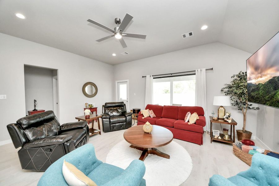 Bathed in natural light from broad windows, this spacious living room features high ceilings and a cool overhead breeze.