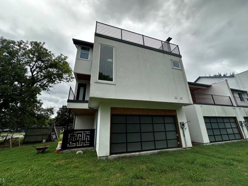 View of side of property with a balcony, a lawn, stucco siding, and a garage