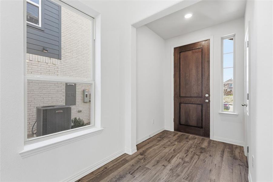 Entryway featuring a rich wood-paneled door, recessed lighting, and wood-finish flooring