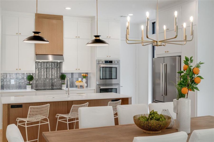 Kitchen featuring hanging light fixtures, backsplash, white cabinetry, appliances with stainless steel finishes, and range hood