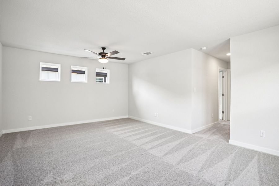 A room with a ceiling fan and a carpet.