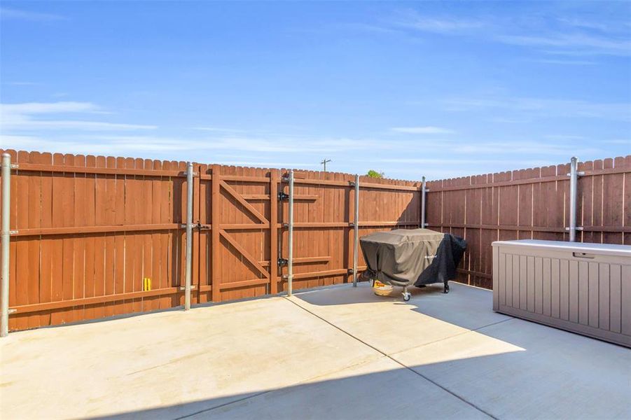 View of patio with a gate and area for grilling