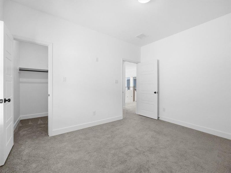 Unfurnished bedroom with a spacious closet and light colored carpet Unfurnished bedroom with a spacious closet and light colored carpet
