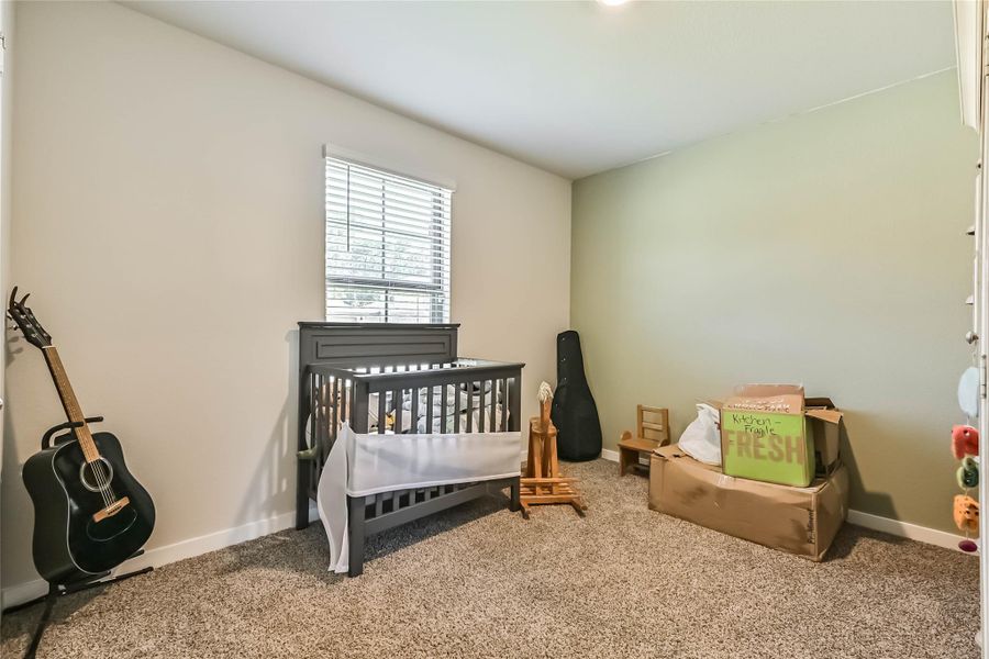 Comfortable secondary bedroom with carpet, ceiling fan, and great natural light—ideal for guests or a home office.
