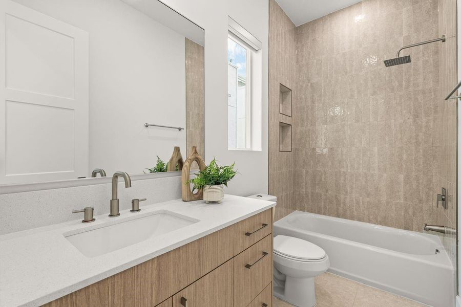 The bathroom pairs generous counter space with a spacious tub-and-shower combination, creating a layout designed for daily ease. Clean detailing and built-in storage niches add both function and visual simplicity.