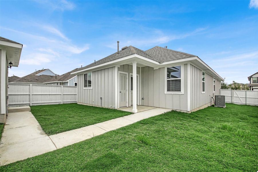 Back of house with board and batten siding, roof with shingles, a fenced backyard, and a patio area