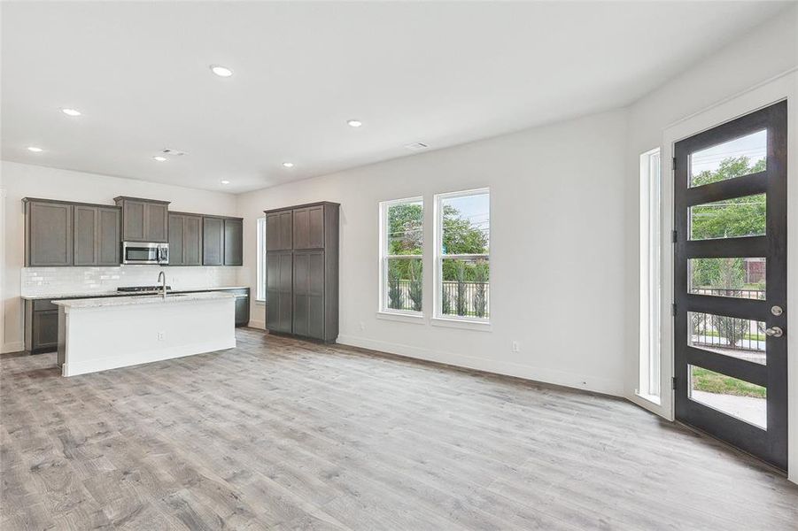 Kitchen with tasteful backsplash, sink, a kitchen island with sink, dark brown cabinetry, and light hardwood / wood-style floors