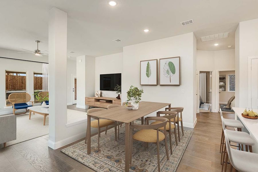 Open-concept dining area with wood table and chairs on a rug, connected to living room with hardwood floors