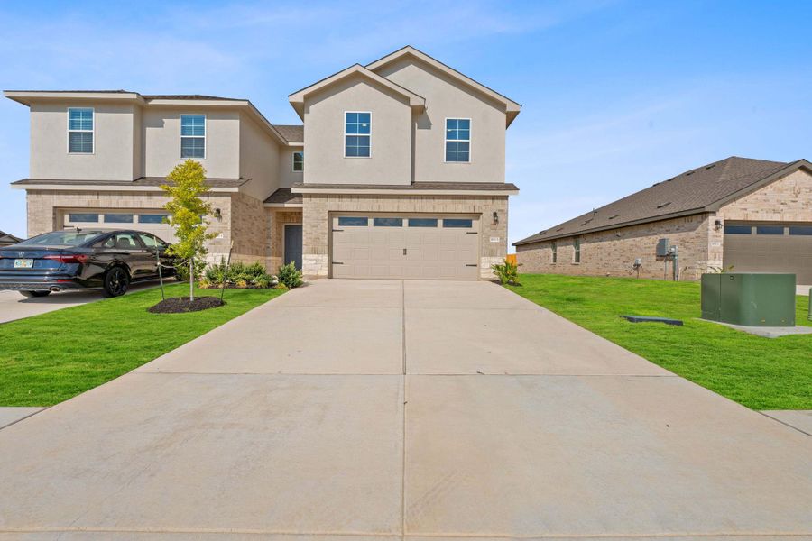 View of front facade with a front lawn, stucco siding, concrete driveway, and brick siding View of front facade with a front lawn, stucco siding, concrete driveway, and brick siding