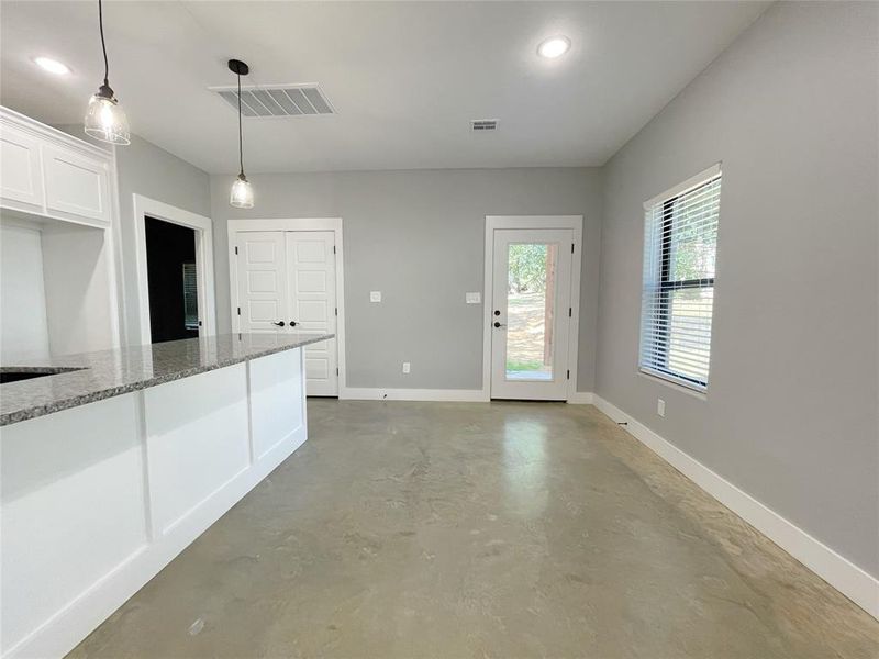 Kitchen with white cabinets, light stone countertops, and pendant lighting