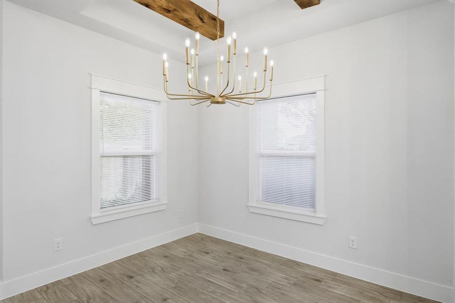 Unfurnished dining area featuring beam ceiling, wood finished floors, and a chandelier