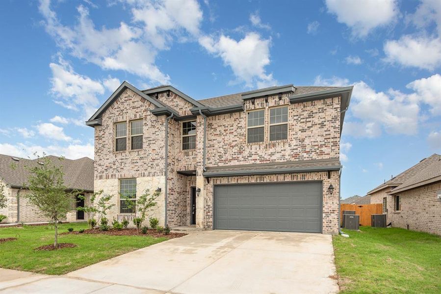 View of front of house with a front yard, central AC, and a garage