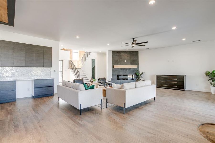Living area featuring light wood-style flooring, recessed lighting, stairway, a fireplace, and a ceiling fan Living area featuring light wood-style flooring, recessed lighting, stairway, a fireplace, and a ceiling fan
