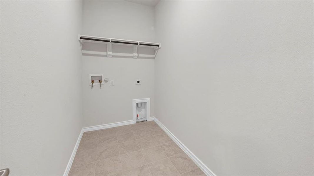 Washroom featuring hookup for an electric dryer, washer hookup, and light tile patterned floors
