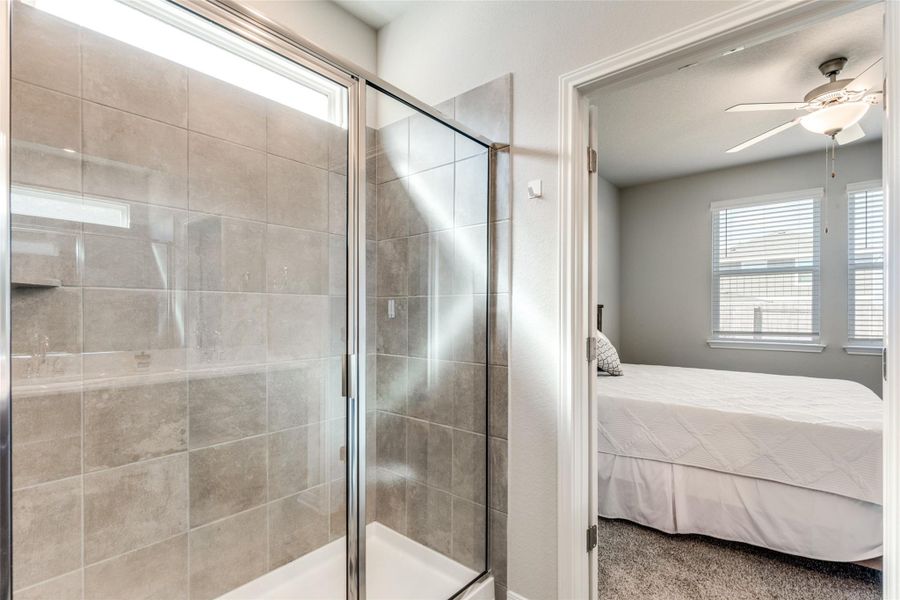 Full bathroom with connected bathroom, plenty of natural light, a shower stall, and ceiling fan