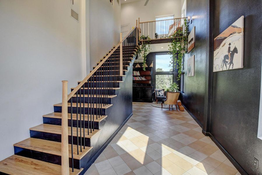 Staircase with plenty of natural light, a high ceiling, and tile patterned floors Staircase with plenty of natural light, a high ceiling, and tile patterned floors