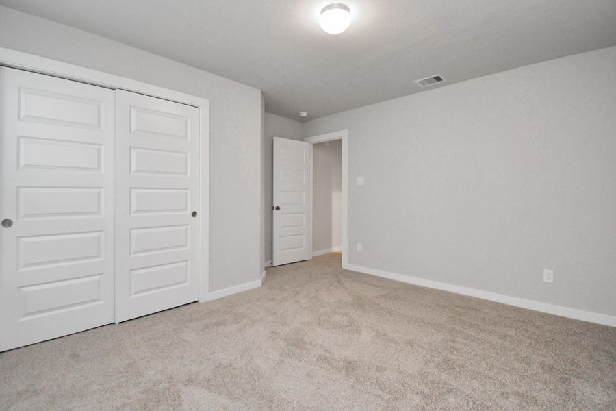 Secondary bedroom features plush carpeting, large windows that let in plenty of natural light, bright paint, and spacious closets. Sample photo of completed home with similar floor plan. Actual colors and selections may vary. Secondary bedroom features plush carpeting, large windows that let in plenty of natural light, bright paint, and spacious closets. Sample photo of completed home with similar floor plan. Actual colors and selections may vary.