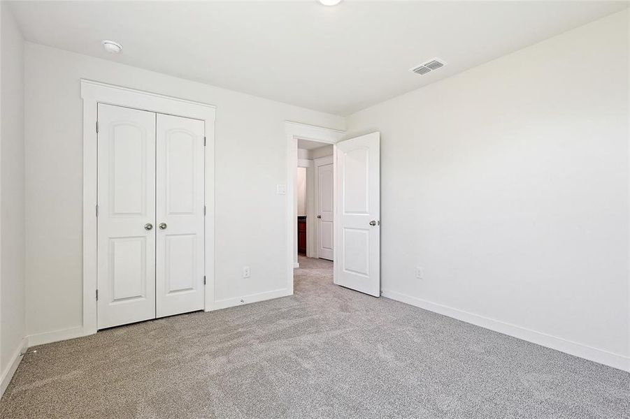 Unfurnished bedroom featuring light carpet and a closet